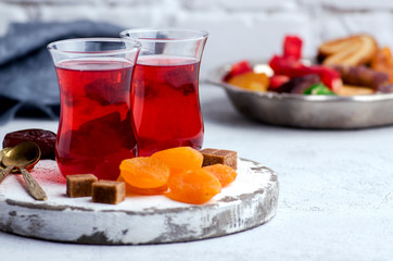 Fruit tea in turkish glasses, oriental sweets, dates and dried apricots. High key