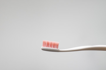 tooth brush with pink bristles on gray background