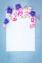 Beautifuil, natural frame with violet pansies and pink roses on blue, fabric background