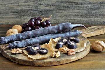 Caucasian delicacy churchkhela with grapes and walnuts on a wooden background close-up.