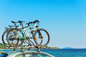 Two bicycle on the roof of the car by the beach.