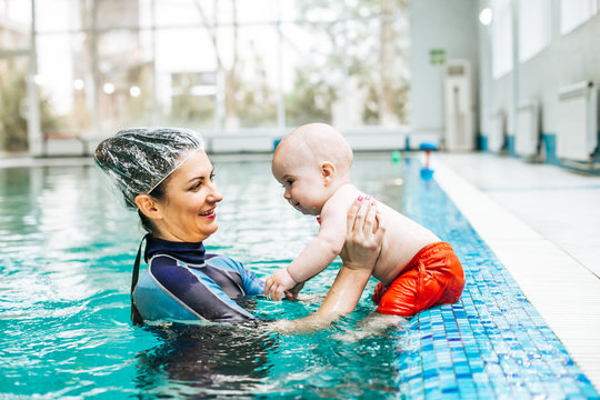 Female instructor teaches kid how to swim. Kid with goggles in w– stock image