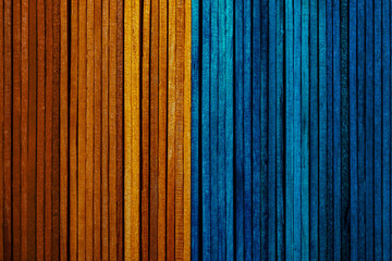 Beautiful texture of natural wood slats of bright orange and blue colors. Vertical sense.