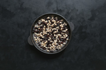 Black and white stewed beans in a pan on the black