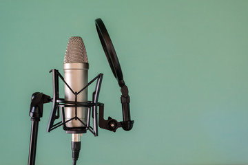 Studio microphone with shock absorber and pop filter on the stand. Close-up. Blue background. Copy...