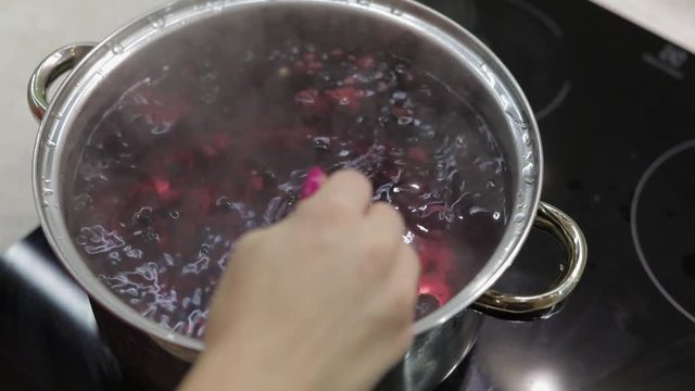 Stir the berries in pot with boiling water. Cooking compote. Kitchen