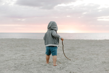 Portrait of Cute Little Baby Boy Child Playing and Exploring in the Sand at the Beach During Sunset Outside on Vacation in Hoodie Zip-Up Sweat Shirt