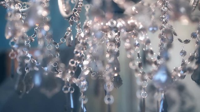 Beautiful chandelier, with transparent pendants and burning lamps, shimmering light, close-up