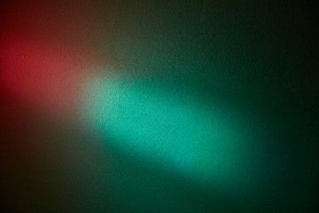 Turquoise spot of light on a dark green textural background with a red glow