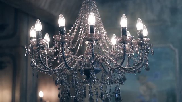 Beautiful chandelier, with transparent pendants and burning lamps.