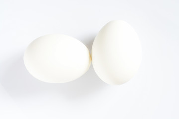 Two white eggs on a white background with shadow