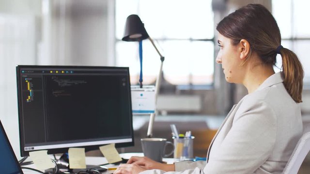 business, programming and technology concept - female programmer with script on computer screen working at office