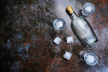 Obraz na płótnie Canvas Bottle of vodka with shot glasses. On stone background.