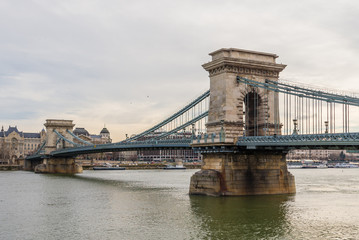 Obraz premium Chain Bridge with Danube river flowing under it as seen from riverside od Danube river in Budapest, Hungary.