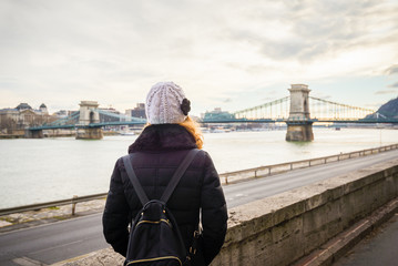Young woman is looking at the Chain bridge from Danube riverbank by the road in Budapest, Hungary.