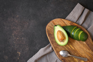 Fresh cut avocado on cutting board over dark background. Napkin linen serving