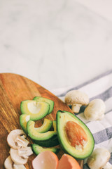 Fresh avocado mushrooms and eggshell on wooden cutting board. White marble background. Striped linen. Rustic
