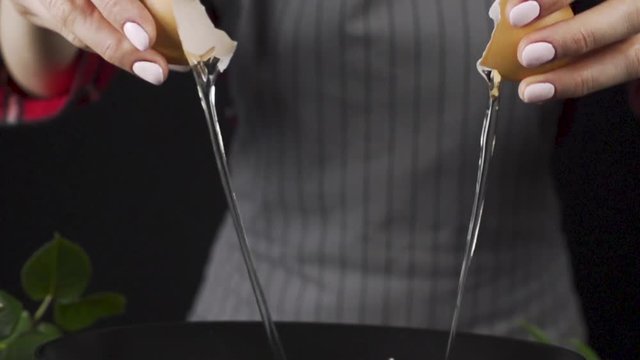 The girl cooks pastries and adds an egg in slow motion side view