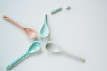 pastel colored ceramic spoons in pink, grey, blue, against white background