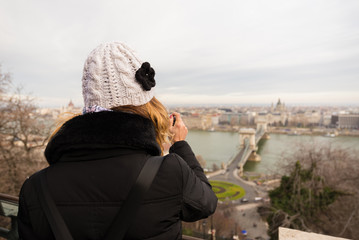 Young woman is taking a photo of Chain Bridge from top. Chain bridge is  suspension bridge that spans the River Danube in Budapest, Hungary.