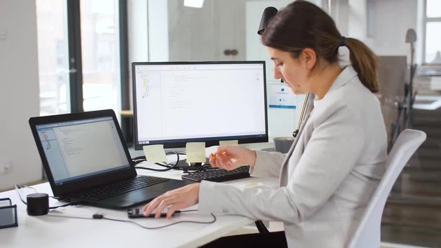 business, programming and technology concept - programmer or businesswoman with smartphone, notebook and computer working at office