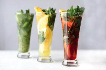 Selection of cocktails red, orange, green cocktails with mint on white background indoor. Food, party, drink, summer concept