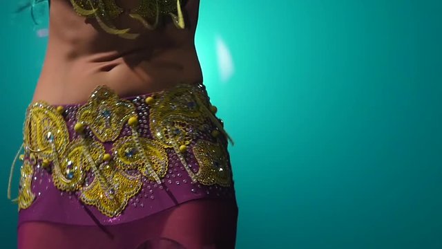 Torso of a exotic female belly dancer . Smoke background. Slow motion. Close up