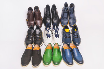 Multicolored men's shoes on a white background. A lot of men's shoes in a row. Types of male shoes. Boots, sneakers and shoes