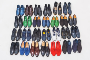 Multicolored men's shoes on a white background. A lot of men's shoes in a row. Types of male shoes. Boots, sneakers and shoes
