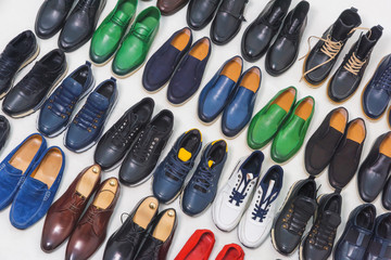 Multicolored men's shoes on a white background. A lot of men's shoes in a row. Types of male shoes. Boots, sneakers and shoes