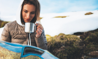 people planning trip in snow mountain, girl hold in hands cup of drinks, relax tourist look on map,...