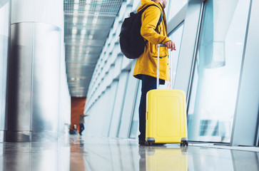 traveler tourist with yellow suitcase backpack at airport on background large window, man waiting...