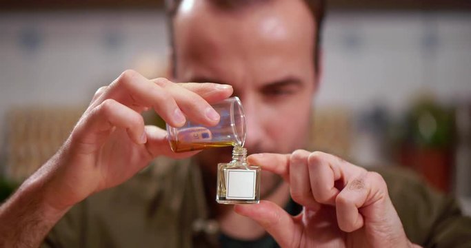 Close up of male perfumer carefully pouring perfume