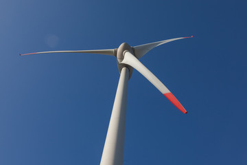 wind turbine with sun flare blue sky background view from below