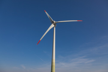 wind turbine with sun flare blue sky background view from below