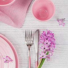 Pink rustic place setting with purple hyacinth flower and linen napkin on white wooden background