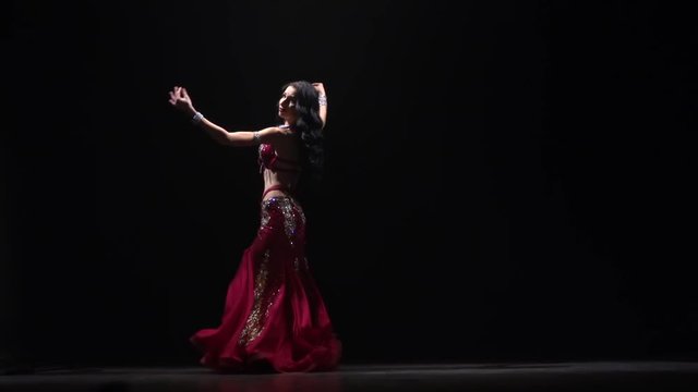 Tempting traditional oriental belly dancer dancing . Black background. Slow motion