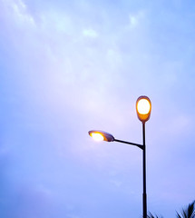 Brightly lit streetlights shining against the blue evening sky.