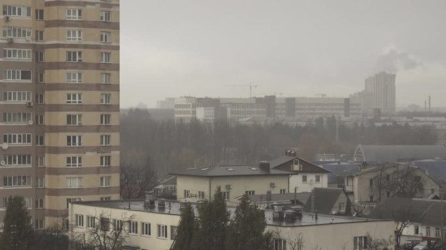 Time lapse in rainy, overcast, foggy weather. Gray, nondescript view of the city of Minsk. Smoke and construction crane. Foggy city suburb apartment buildings. Fog and mist urban landscape. Raindrops.