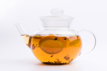 Glass teapot with herbal tea nad fresh orange isolated on white background