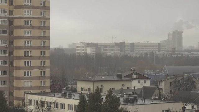 Time lapse in rainy, overcast, foggy weather. Gray, nondescript view of the city of Minsk. Smoke and construction crane. Foggy city suburb apartment buildings. Fog and mist urban landscape. Raindrops.