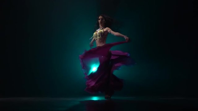 Girl with a veil in her hands dancing belly dance . Smoke background. Slow motion