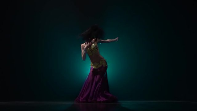 Woman belly dancer arabian in exotic dress dancing. Smoke background. Slow motion