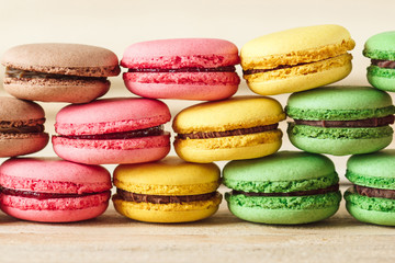 Obraz na płótnie Canvas Green, pink, yellow and brown french macarons on the wooden boards