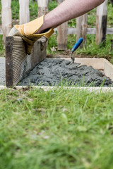 Man wearing protective work gloves leveling fresh cement