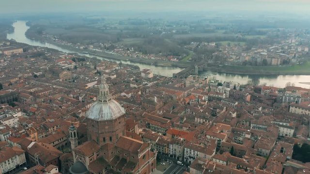 Aerial shot of Duomo di Pavia cathedral and the Ponte Coperto Bridge within the cityscape of Pavia, Italy