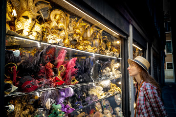 Young woman who chois a Venetian mask in shop
