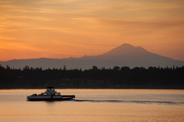 Ferry Boat With Mt. Baker in the Background. A small ferry boat from Lummi Island, Washington, makes the crossing to Gooseberry Point on the mainland near the city of Bellingham.