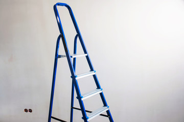 Ladder in the room in new house or flat. Preparing to paint the wall or wall covering pasting wallpaper. Painting tools on a metal ladder. Home renovation concept. White background isolated copyspace