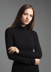 young caucasian brownhair woman in black turtleneck isolated on gray background